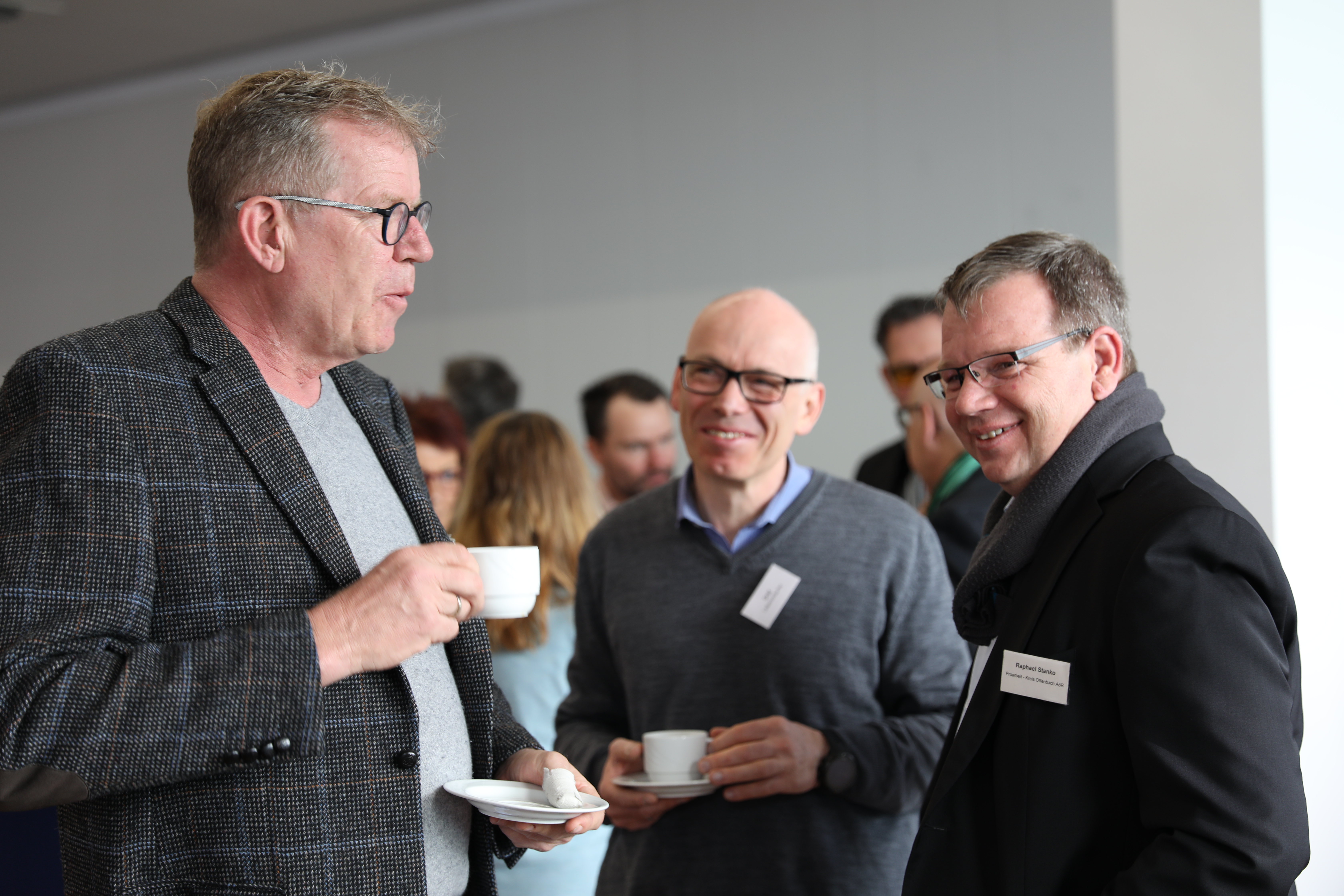 Männer unterhalten sich freudig und trinken einen Kaffee